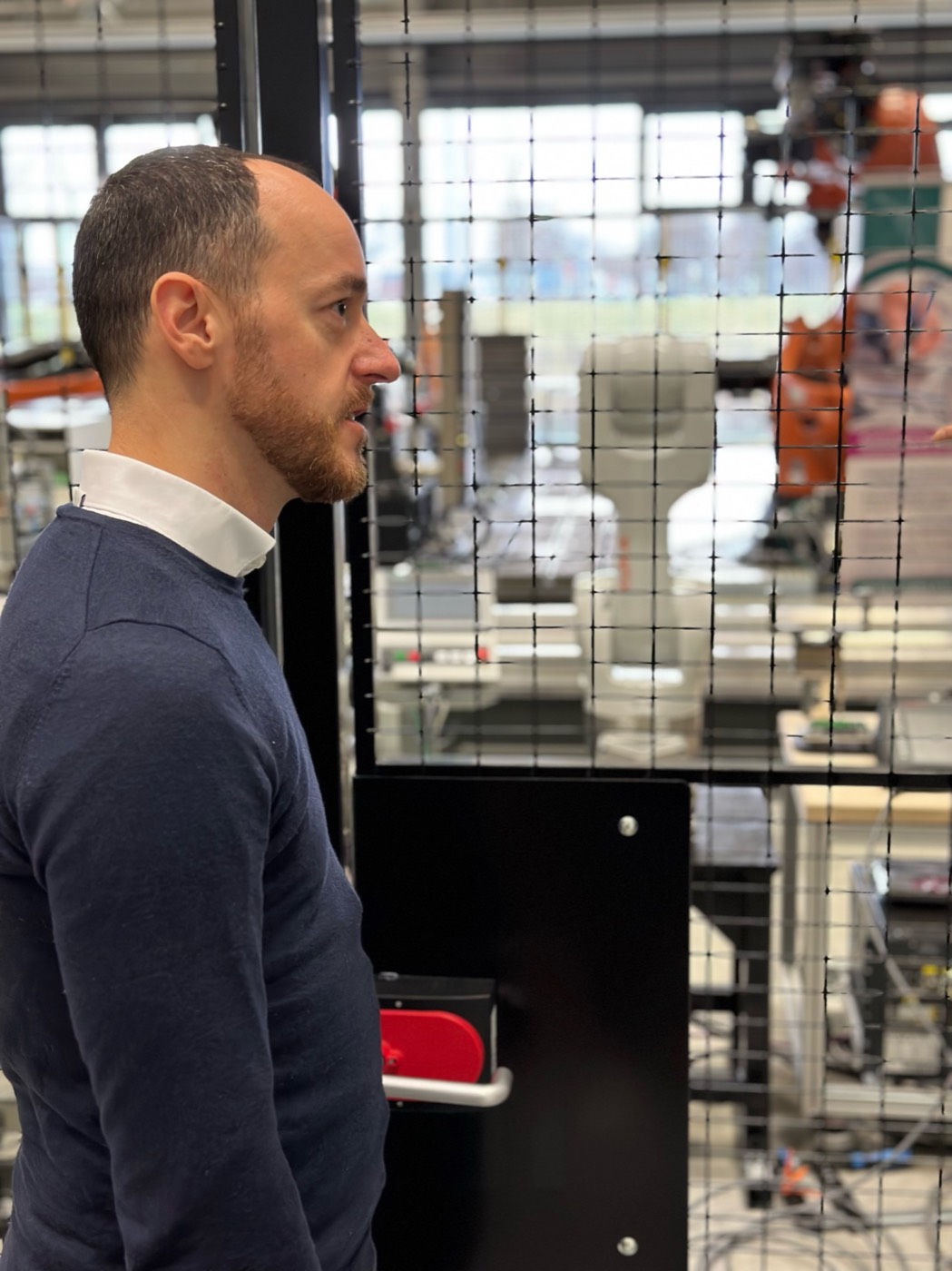 Martin Posarnig vor einer Roboterzelle in einer Produktionshalle